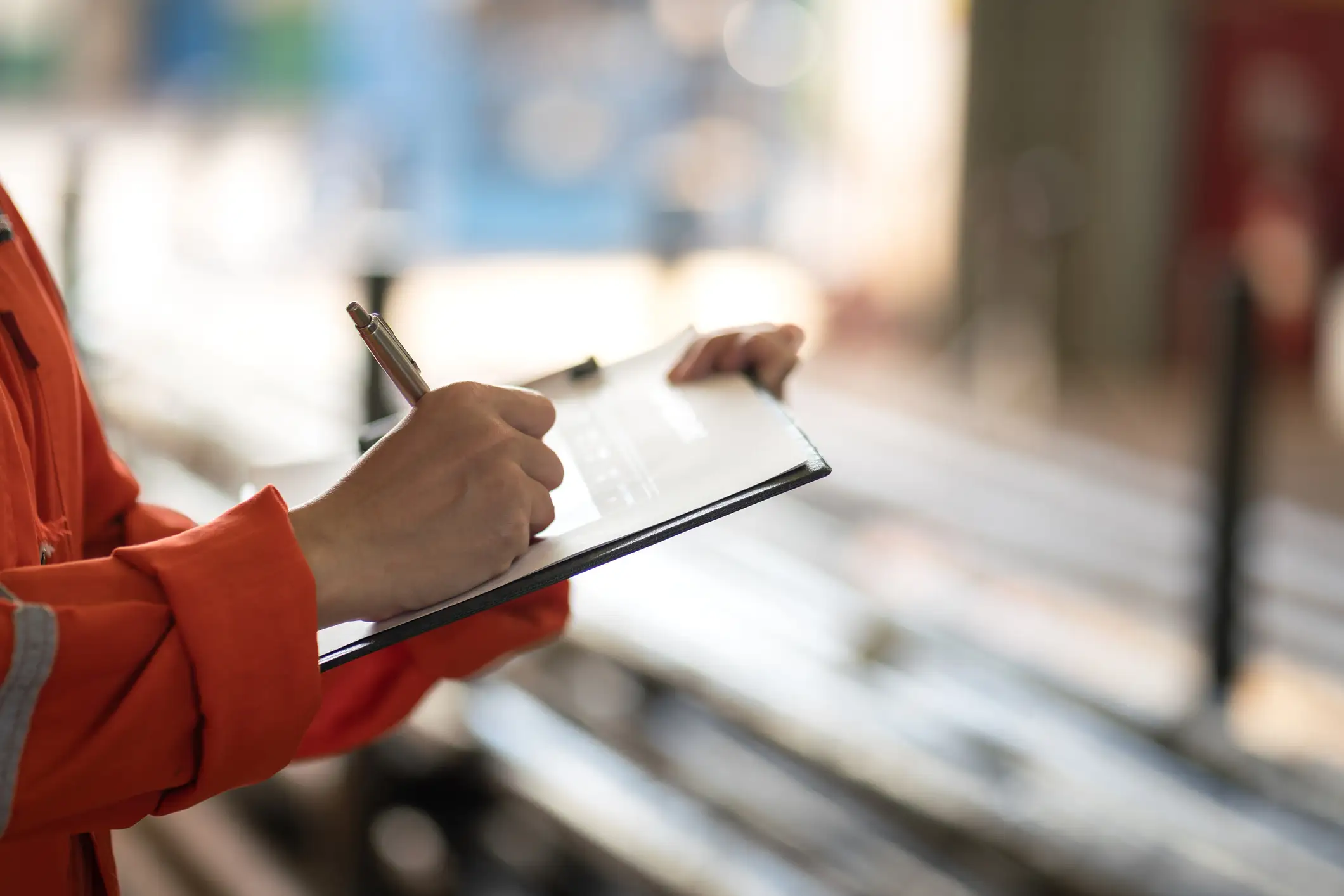 Fire safety inspector in an orange protective uniform completing an inspection checklist on a clipboard.
